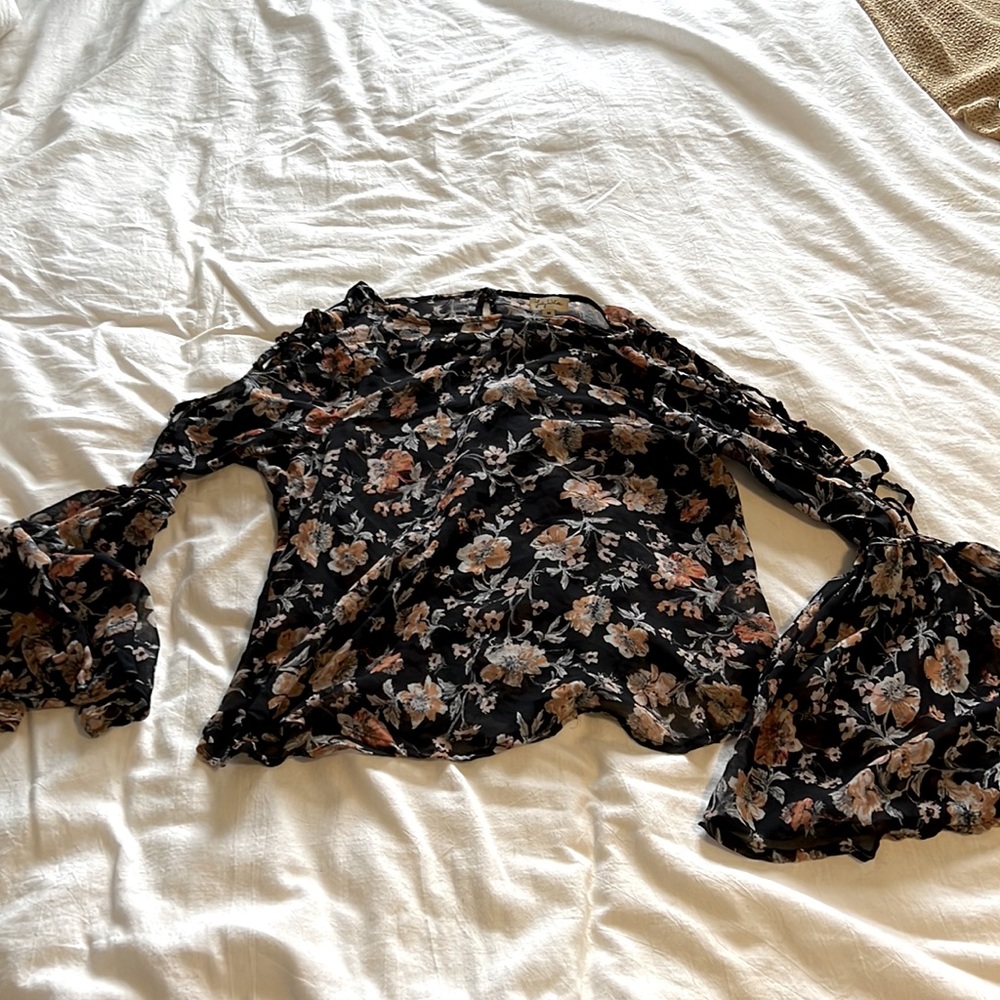 Floral top with bell sleeves and ties up the arm.